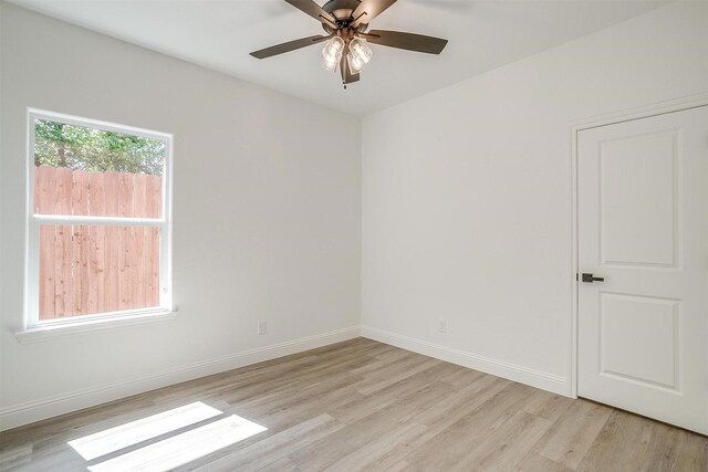 spare room featuring light wood finished floors, baseboards, and a ceiling fan