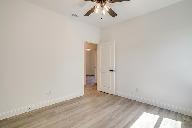 spare room with visible vents, light wood finished floors, baseboards, and a ceiling fan
