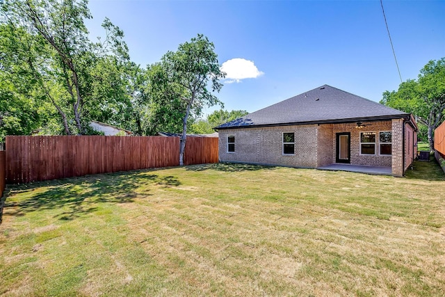 rear view of property with a fenced backyard, brick siding, a yard, and a patio