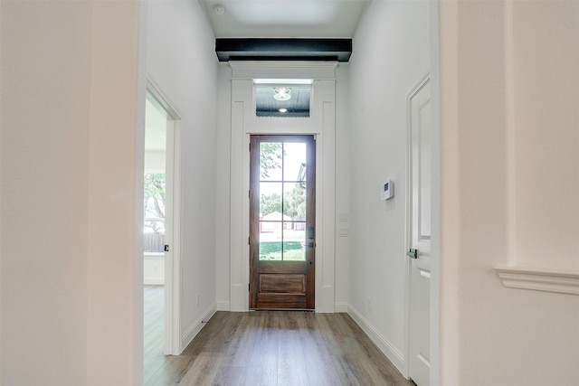 doorway featuring baseboards and wood finished floors