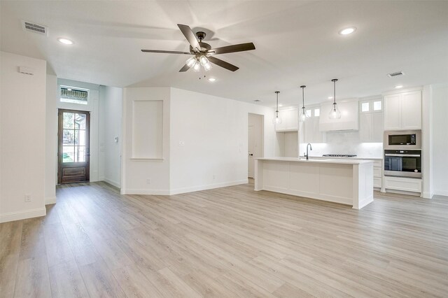 unfurnished living room with a ceiling fan, a sink, visible vents, and light wood-type flooring