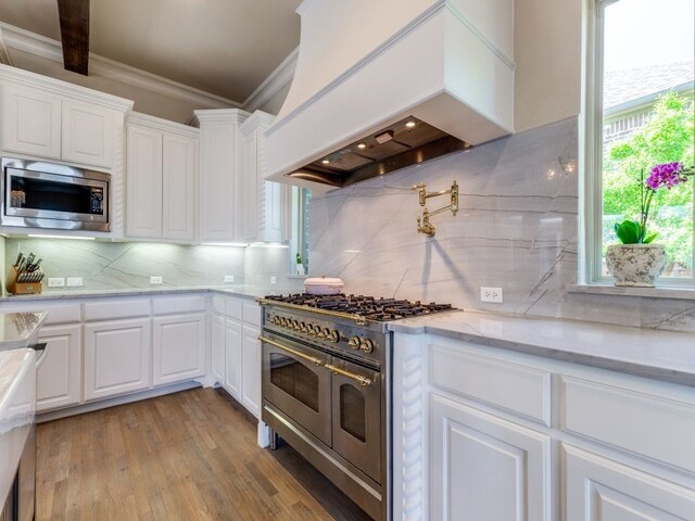 kitchen featuring custom exhaust hood, appliances with stainless steel finishes, crown molding, and decorative backsplash