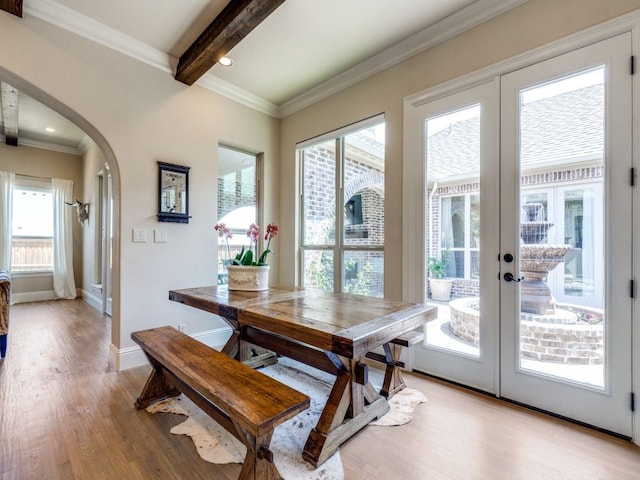 dining area featuring a healthy amount of sunlight, french doors, light wood finished floors, and arched walkways