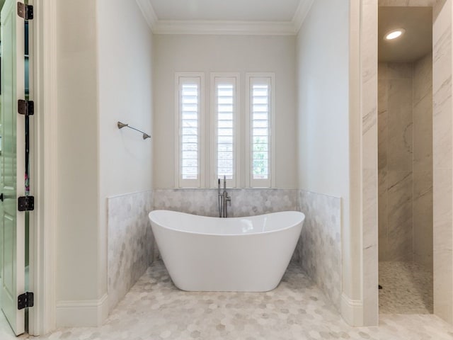 full bath featuring tile walls, a freestanding tub, a tile shower, a wainscoted wall, and ornamental molding