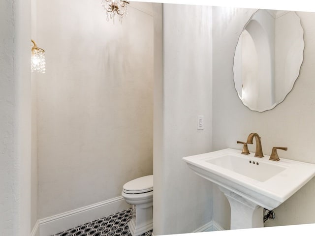 half bath featuring a sink, toilet, and baseboards