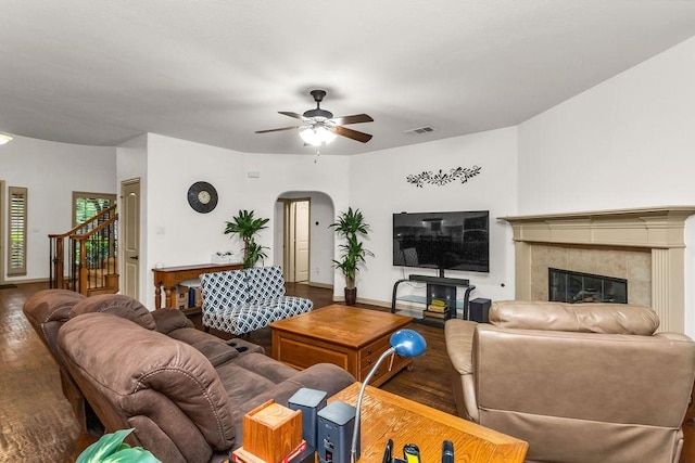 living area featuring a fireplace, ceiling fan, visible vents, arched walkways, and wood finished floors