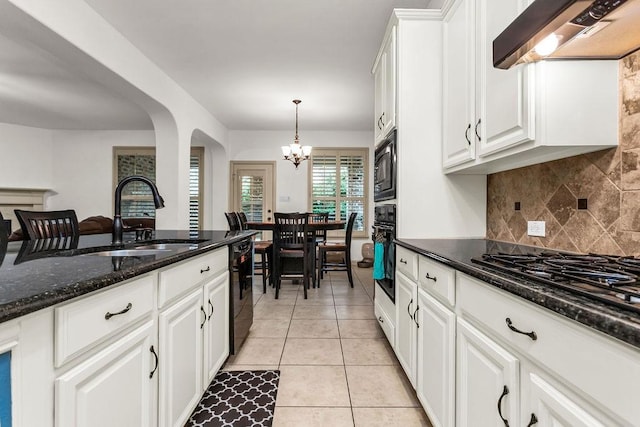 kitchen featuring a sink, a notable chandelier, tasteful backsplash, wall chimney exhaust hood, and black appliances