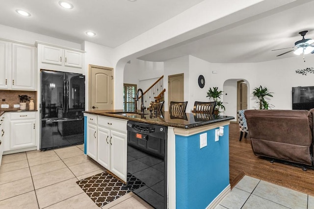kitchen with black appliances, a sink, open floor plan, and arched walkways