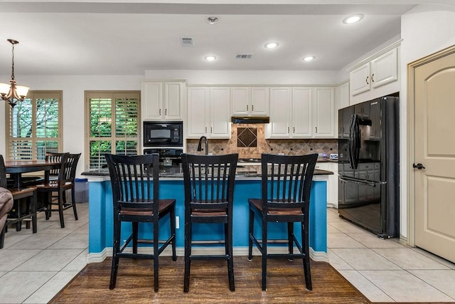 kitchen featuring white cabinets, black appliances, visible vents, a notable chandelier, and light tile patterned flooring
