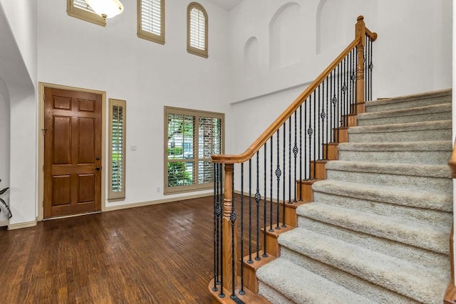 entrance foyer featuring baseboards, stairway, wood finished floors, and a healthy amount of sunlight