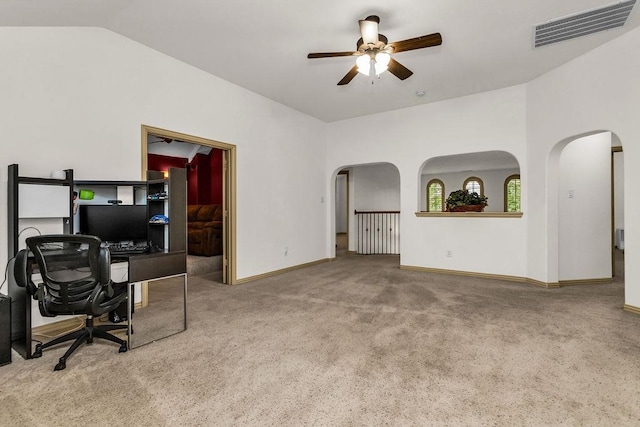 carpeted office space featuring arched walkways, vaulted ceiling, ceiling fan, baseboards, and visible vents