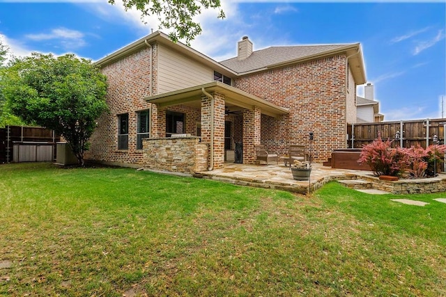 back of house with a chimney, a jacuzzi, brick siding, fence, and a patio
