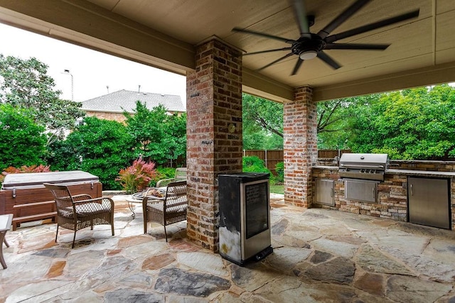 view of patio / terrace featuring exterior kitchen, area for grilling, a hot tub, ceiling fan, and fence