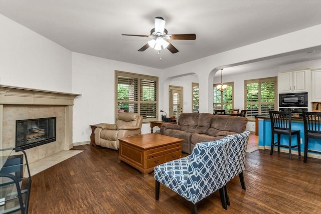 living area with dark wood-style flooring, plenty of natural light, a ceiling fan, and arched walkways