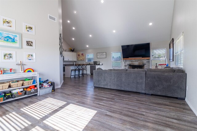 living area featuring recessed lighting, wood finished floors, visible vents, baseboards, and high vaulted ceiling