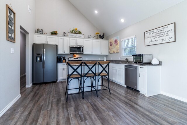 kitchen with white cabinets, stainless steel appliances, baseboards, and high vaulted ceiling