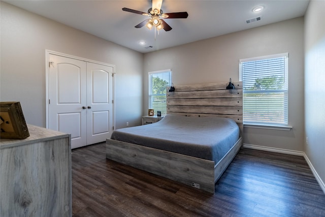 bedroom featuring dark wood-style floors, baseboards, visible vents, and a closet