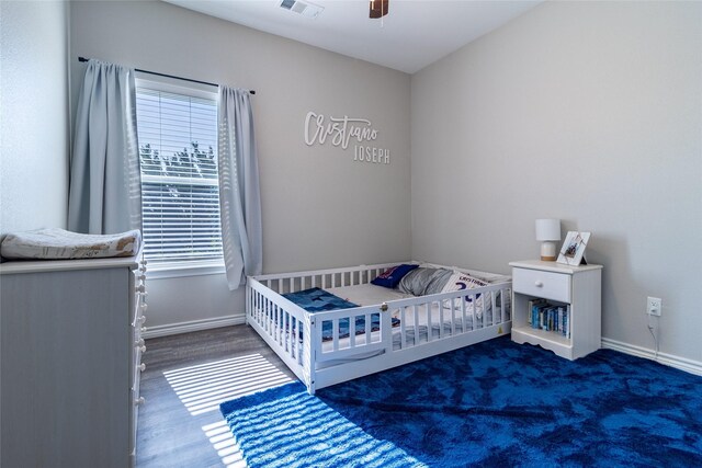 bedroom with visible vents, a crib, a ceiling fan, and baseboards