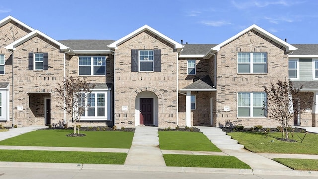 townhome / multi-family property featuring brick siding and a front yard