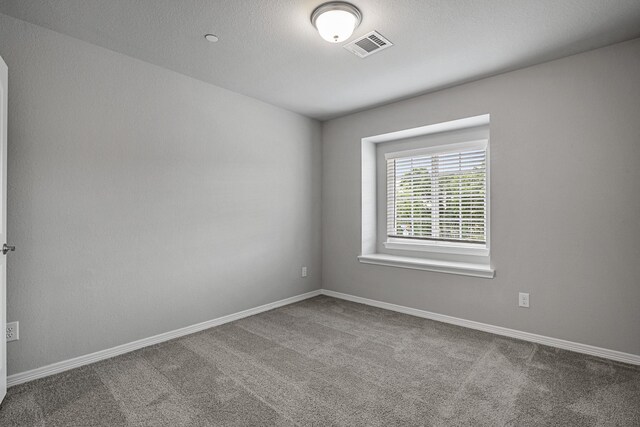 carpeted empty room featuring baseboards and visible vents