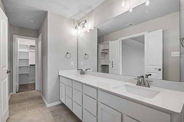 bathroom featuring baseboards, visible vents, a sink, and double vanity
