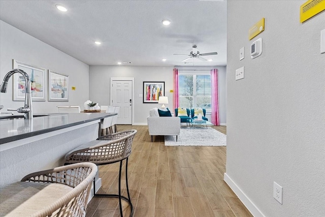 interior space with baseboards, a sink, a breakfast bar, and light wood-style flooring