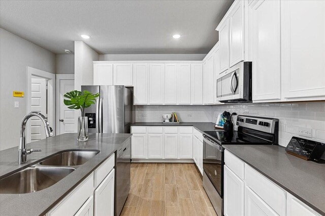 kitchen featuring backsplash, white cabinetry, stainless steel appliances, and a sink