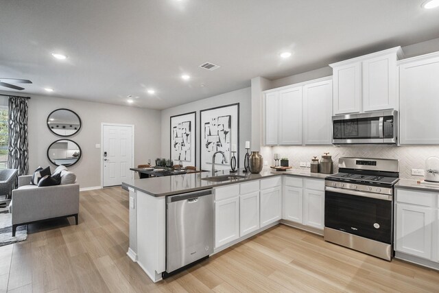 kitchen with light wood finished floors, a sink, open floor plan, visible vents, and appliances with stainless steel finishes