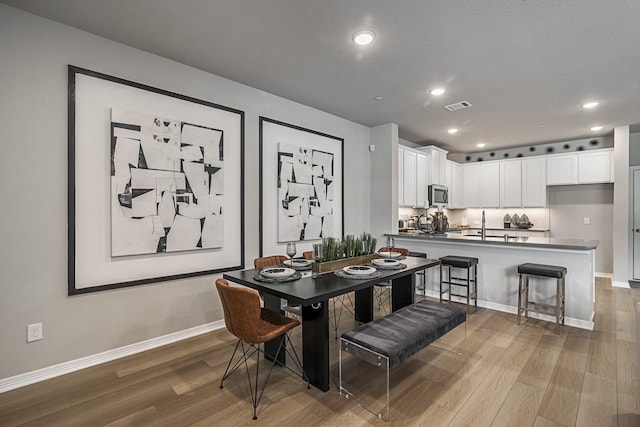 dining area with visible vents, baseboards, and wood finished floors