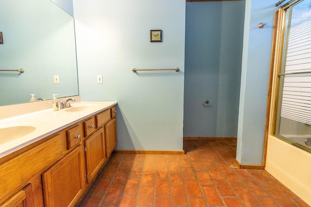 full bath with baseboards, a sink, bath / shower combo with glass door, and double vanity