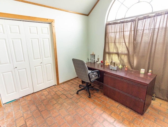office space featuring baseboards, lofted ceiling, crown molding, and built in desk