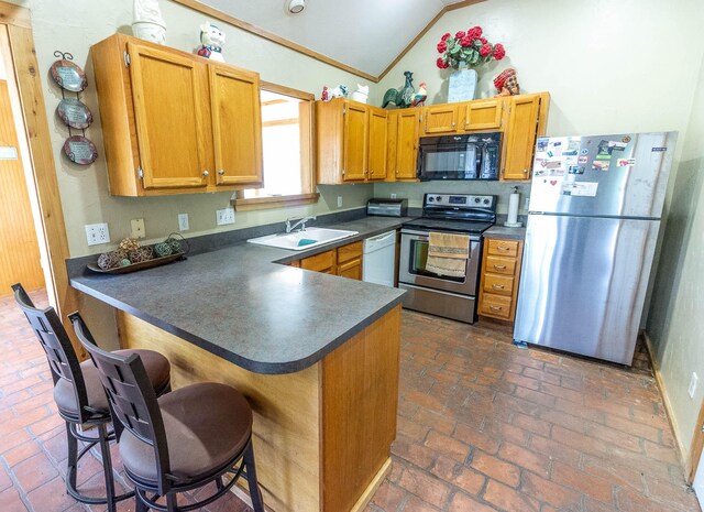 kitchen featuring vaulted ceiling, dark countertops, a sink, brick floor, and appliances with stainless steel finishes