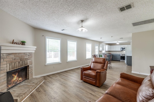 4504 Courtside Dr, Mckinney, TX 75070 - living area with light wood-type flooring, a fireplace, a textured ceiling, and baseboards