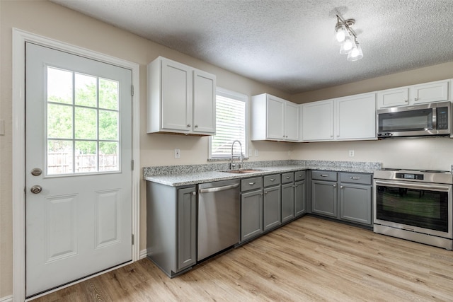 4504 Courtside Dr, Mckinney, TX 75070 - kitchen featuring appliances with stainless steel finishes, a sink, gray cabinets, a textured ceiling, and light wood finished floors