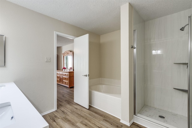 4504 Courtside Dr, Mckinney, TX 75070 - bathroom with a shower stall, wood finished floors, a textured ceiling, a garden tub, and vanity