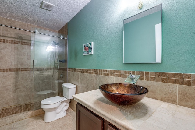 4504 Courtside Dr, Mckinney, TX 75070 - bathroom with toilet, tiled shower, vanity, a textured ceiling, and tile walls