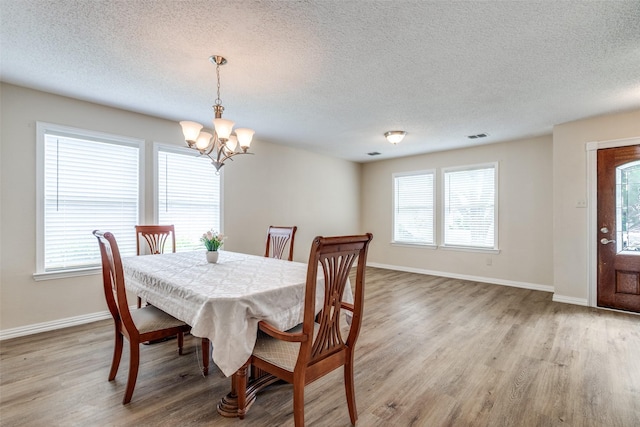 4504 Courtside Dr, Mckinney, TX 75070 - dining room with a chandelier, light wood-style flooring, a textured ceiling, and baseboards