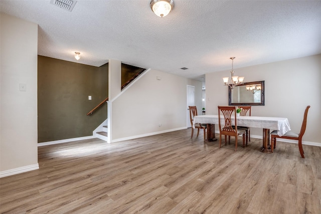 4504 Courtside Dr, Mckinney, TX 75070 - dining space featuring a textured ceiling, light wood-style floors, a chandelier, stairs, and baseboards