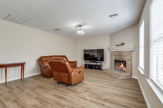 4504 Courtside Dr, Mckinney, TX 75070 - living area with light wood-style flooring, a textured ceiling, a fireplace, and baseboards