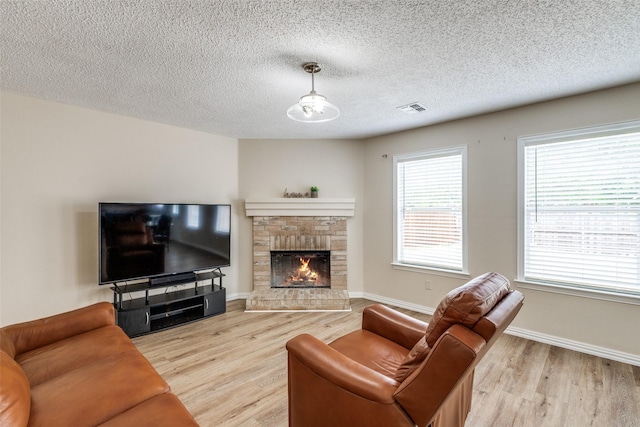 4504 Courtside Dr, Mckinney, TX 75070 - living area with light wood-style floors, a textured ceiling, a brick fireplace, and baseboards