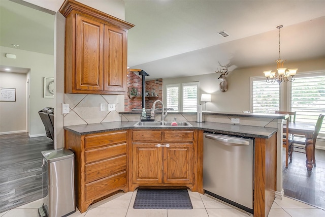kitchen featuring a peninsula, dishwasher, brown cabinetry, and a sink
