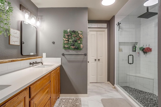 full bathroom with a shower stall, a sink, marble finish floor, double vanity, and baseboards