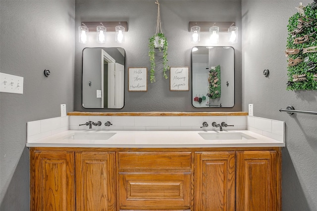 full bath featuring backsplash, a textured wall, a sink, and double vanity