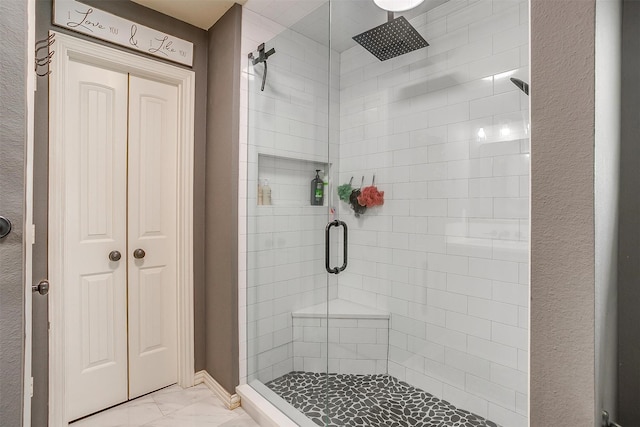 bathroom with marble finish floor and a stall shower
