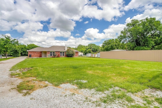 view of yard with an attached garage, driveway, and fence