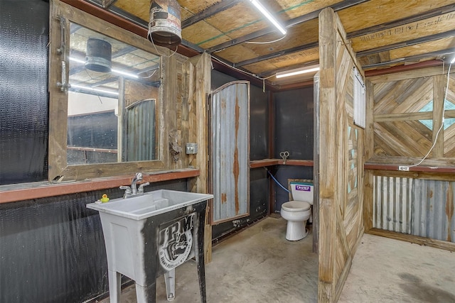 bathroom with unfinished concrete flooring and toilet