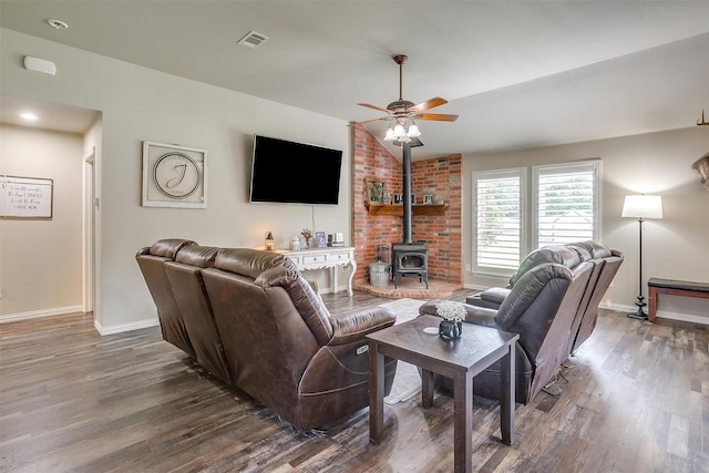living room featuring ceiling fan, a wood stove, wood finished floors, and visible vents