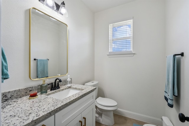 half bath featuring baseboards, toilet, and vanity