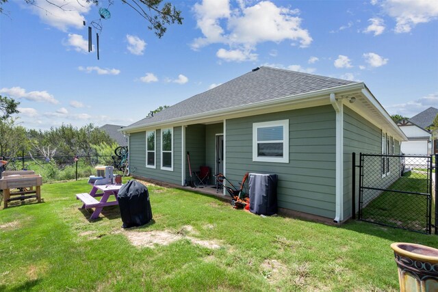 rear view of property with a lawn, a gate, fence, and roof with shingles