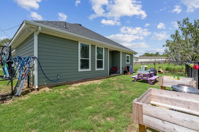 back of property with a lawn, a shingled roof, and a fenced backyard